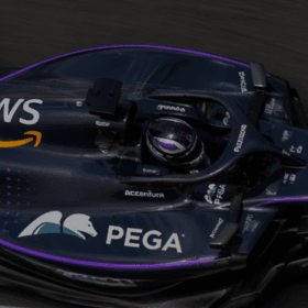Top-down view of a dark blue Formula 1 car with AWS and Accenture branding on a race track, purple accents visible along the body.